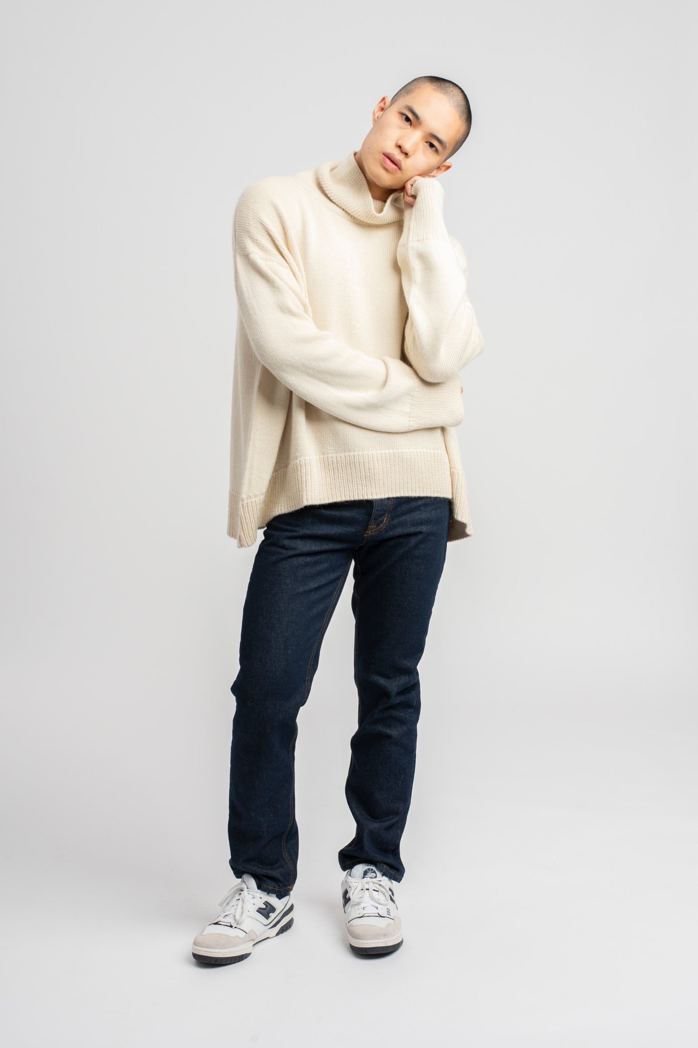 Model wearing turtleneck oversized sweater in white alpaca wool, head to side